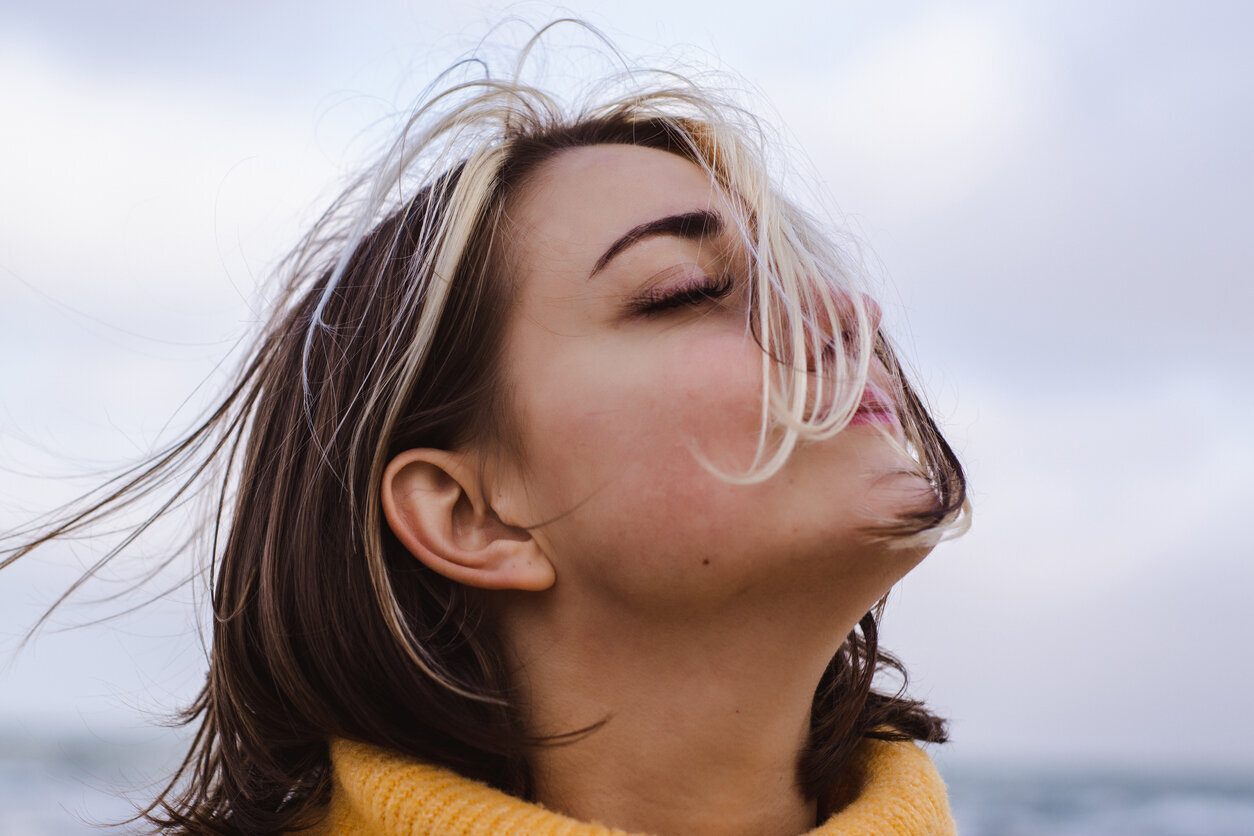 Woman with closed eyes and wind blowing through her hair